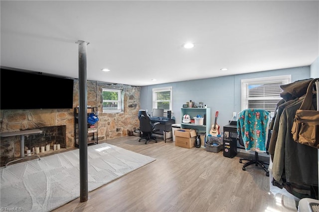 office area featuring a stone fireplace, recessed lighting, and wood finished floors