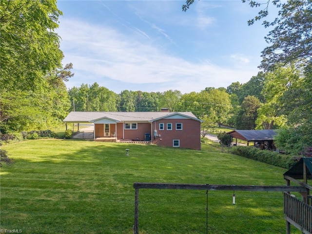 rear view of house with a yard, a forest view, and fence