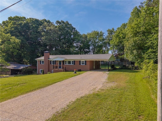 view of front of house with dirt driveway, a chimney, an attached carport, and a front lawn