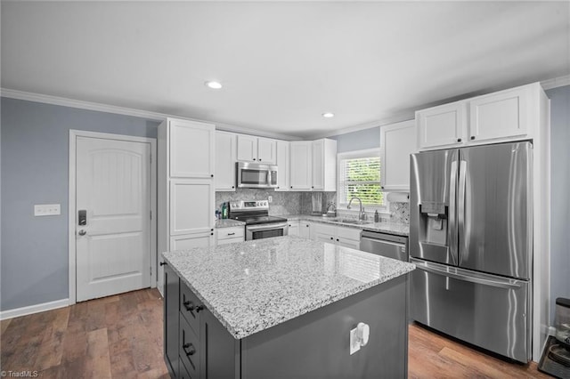 kitchen featuring white cabinetry, stainless steel appliances, ornamental molding, and a sink
