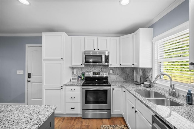 kitchen featuring crown molding, appliances with stainless steel finishes, white cabinetry, and a sink