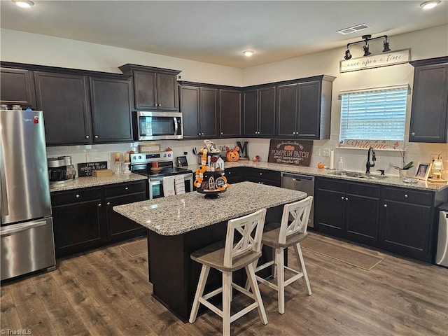 kitchen with dark hardwood / wood-style floors, a kitchen island, sink, and stainless steel appliances