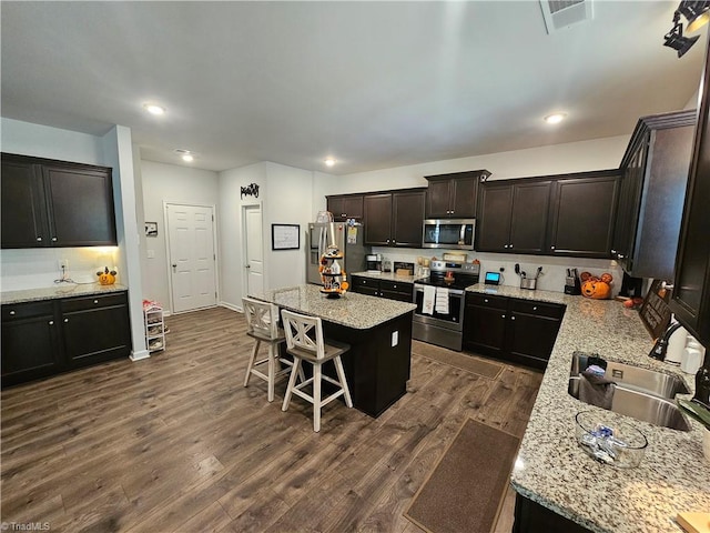 kitchen featuring sink, appliances with stainless steel finishes, dark wood-type flooring, and a center island