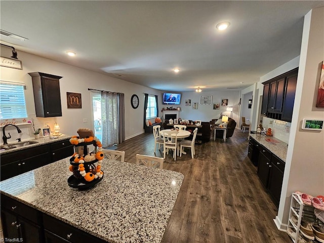 kitchen featuring light stone countertops, sink, dark hardwood / wood-style flooring, and a kitchen island