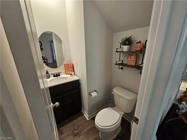 bathroom featuring wood-type flooring, vaulted ceiling, vanity, and toilet