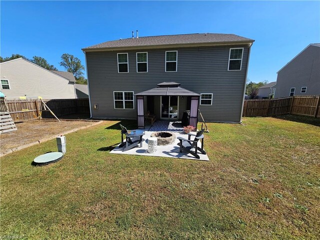 back of property with a fire pit, a lawn, and a patio area