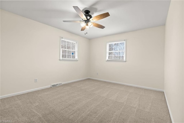 empty room featuring light carpet, visible vents, a ceiling fan, and baseboards