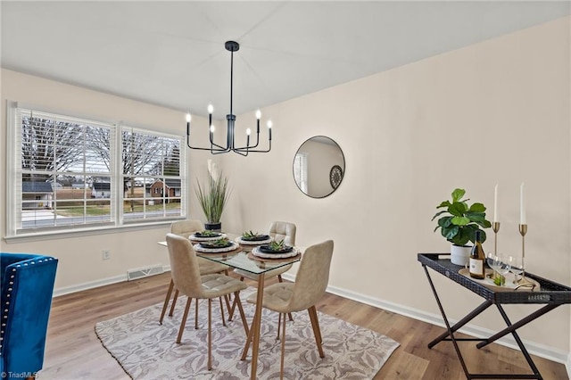 dining space featuring visible vents, wood finished floors, baseboards, and a chandelier