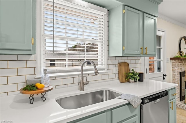 kitchen with green cabinets, a sink, decorative backsplash, light countertops, and stainless steel dishwasher