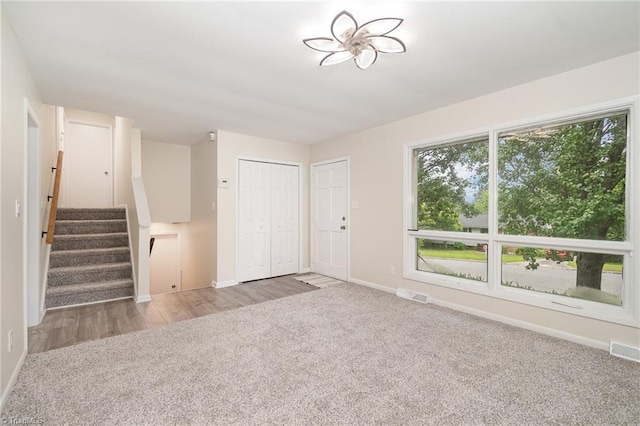 2102 Castlerock Rd, Greensboro, NC 27406 - unfurnished living room with baseboards, stairway, and carpet flooring