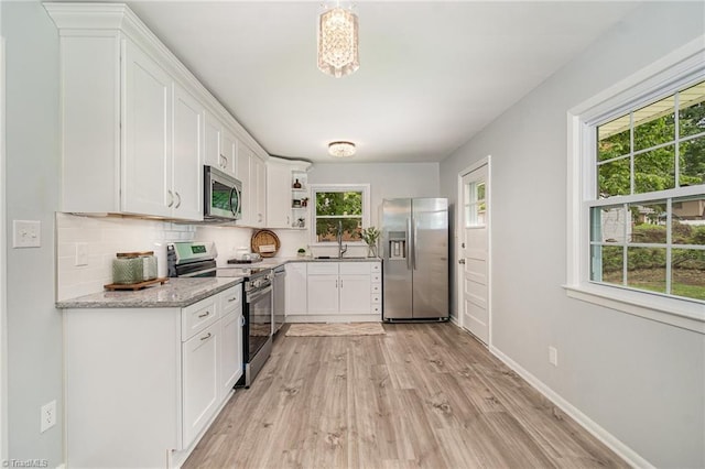 2102 Castlerock Rd, Greensboro, NC 27406 - kitchen featuring appliances with stainless steel finishes, plenty of natural light, light wood-type flooring, and white cabinets