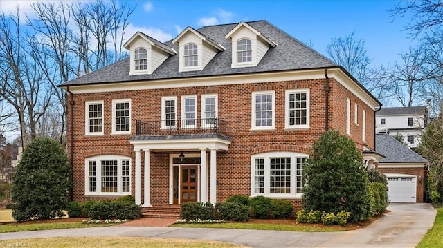 colonial-style house with brick siding, concrete driveway, a garage, and a shingled roof