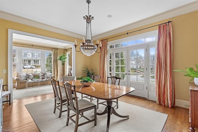 dining room featuring light wood finished floors, french doors, crown molding, and baseboards