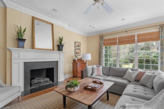 living room with baseboards, a fireplace with flush hearth, light wood-type flooring, ornamental molding, and a ceiling fan