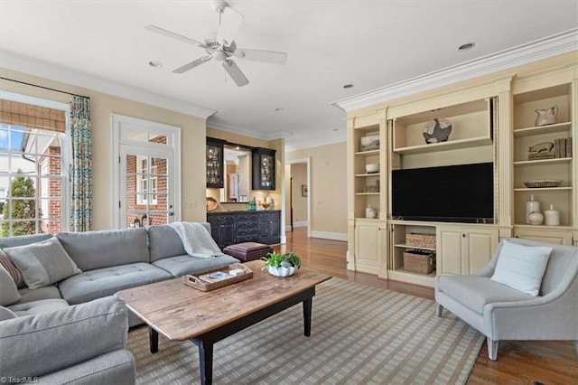 living area featuring ceiling fan, baseboards, wood finished floors, and ornamental molding