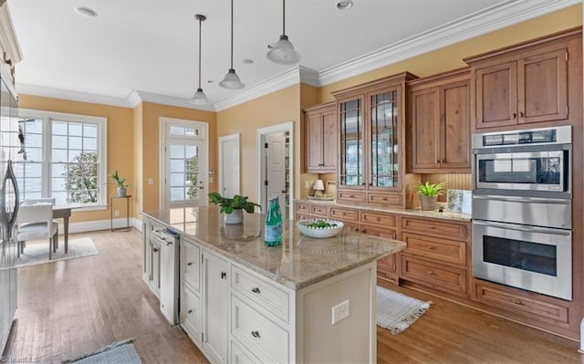 kitchen with light wood-type flooring, ornamental molding, a kitchen island, double oven, and brown cabinetry