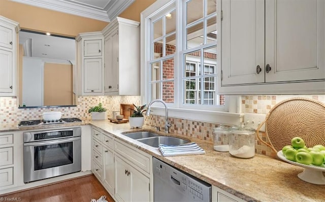 kitchen featuring a sink, tasteful backsplash, white cabinetry, stainless steel appliances, and crown molding