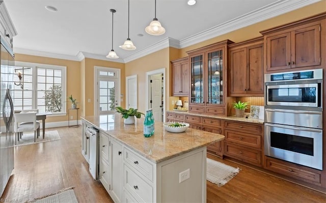 kitchen with a center island, crown molding, double oven, light wood-style flooring, and brown cabinetry