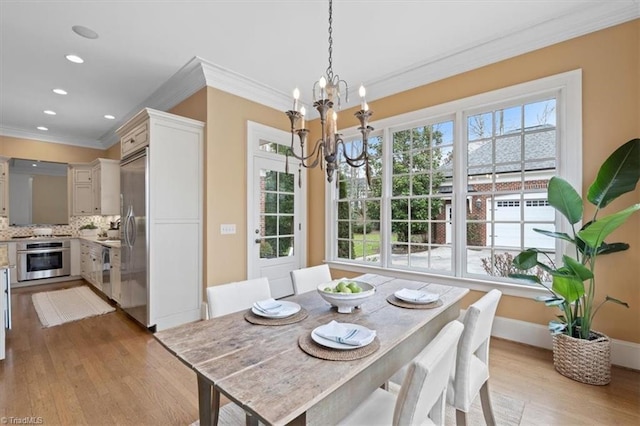 dining area featuring a notable chandelier, light wood-style floors, a healthy amount of sunlight, and crown molding