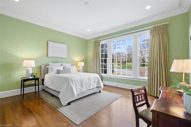 bedroom featuring recessed lighting, wood finished floors, baseboards, and ornamental molding