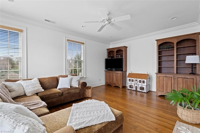 living area with crown molding, wood finished floors, and visible vents