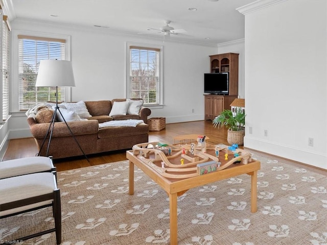 living area featuring a ceiling fan, crown molding, baseboards, and wood finished floors