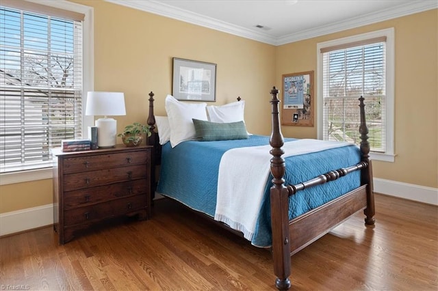 bedroom featuring visible vents, crown molding, baseboards, and wood finished floors