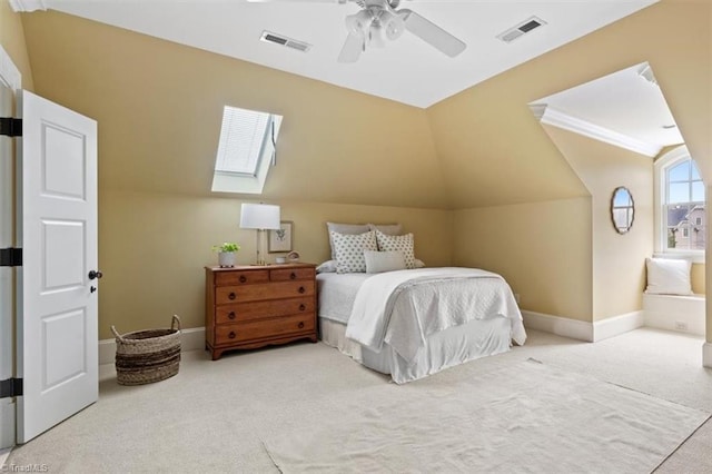 carpeted bedroom with visible vents, lofted ceiling with skylight, baseboards, and a ceiling fan