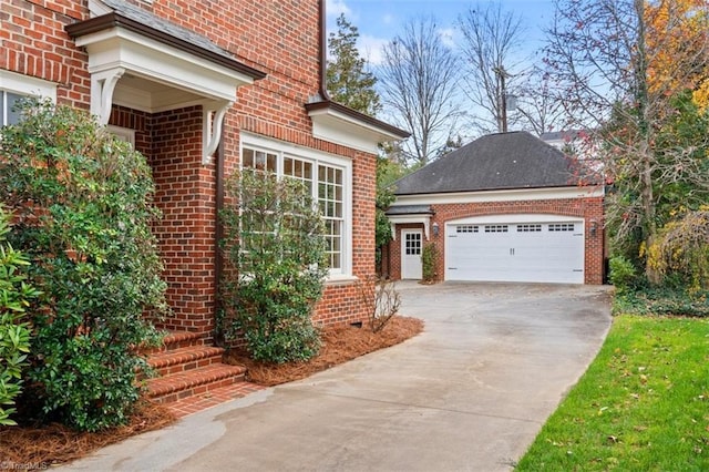 view of side of home with concrete driveway, a garage, an outbuilding, and brick siding