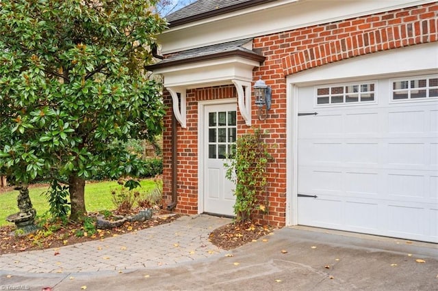 view of exterior entry with brick siding, driveway, and a garage