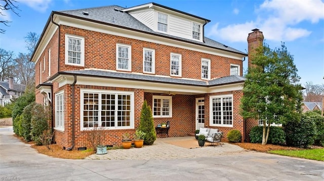 back of house with a patio, brick siding, and a shingled roof