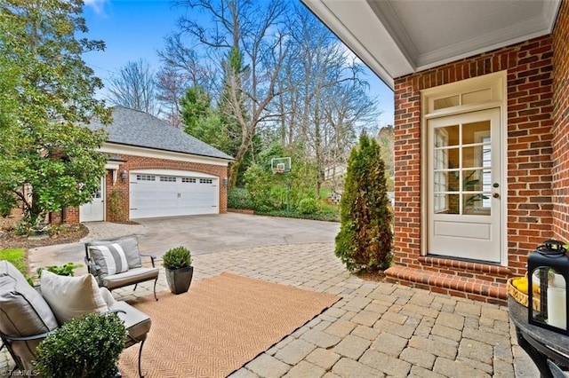 view of patio / terrace featuring an outbuilding, an attached garage, and driveway