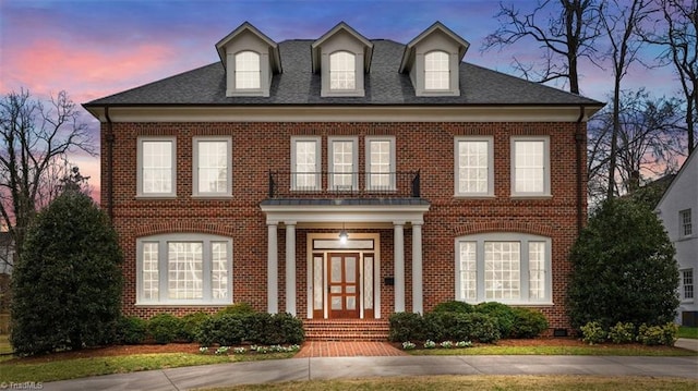 colonial inspired home with brick siding and a shingled roof