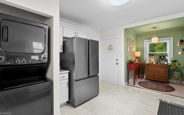 209 Burtner St, Greensboro, NC 27406 - kitchen with freestanding refrigerator, stacked washer and clothes dryer, white cabinets, ornamental molding, and hanging light fixtures