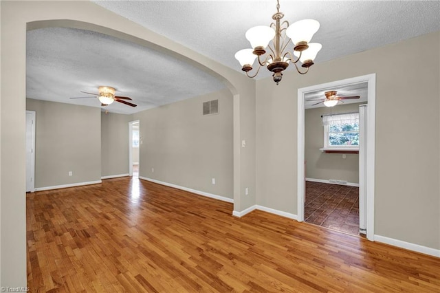 unfurnished room with ceiling fan with notable chandelier, a textured ceiling, and hardwood / wood-style flooring