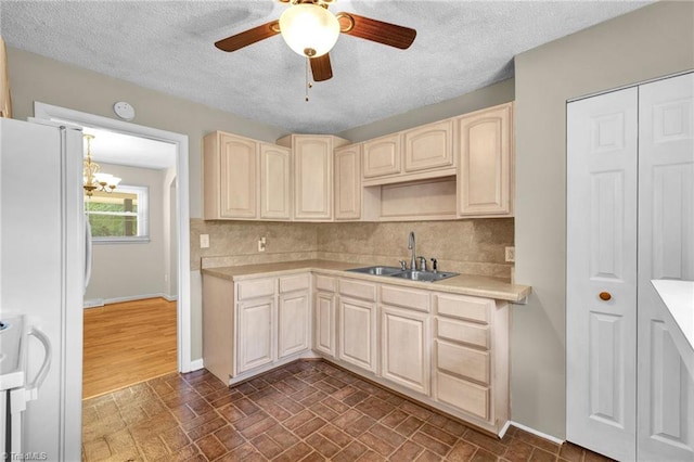 kitchen featuring a textured ceiling, ceiling fan with notable chandelier, sink, and white refrigerator