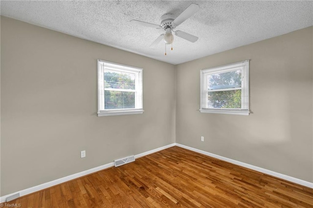 unfurnished room featuring ceiling fan, plenty of natural light, hardwood / wood-style floors, and a textured ceiling