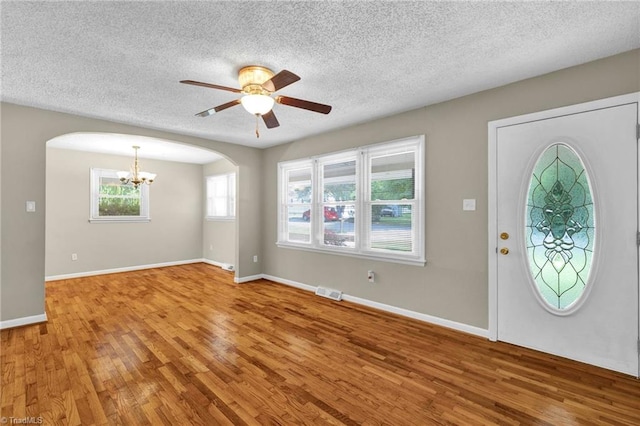 entrance foyer featuring ceiling fan with notable chandelier, wood-type flooring, and a textured ceiling