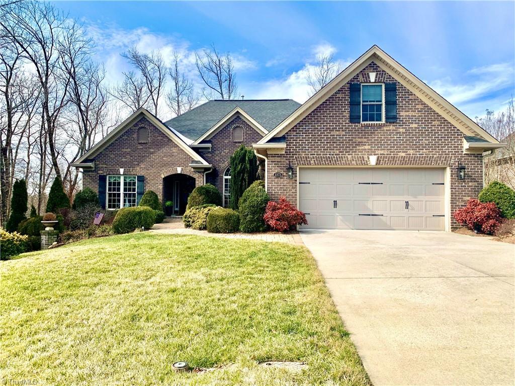 traditional-style home featuring concrete driveway, an attached garage, brick siding, and a front yard