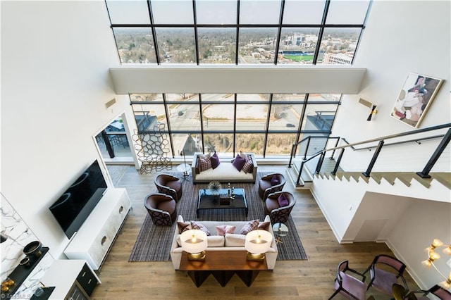 living area featuring visible vents, stairway, a high ceiling, wood finished floors, and baseboards