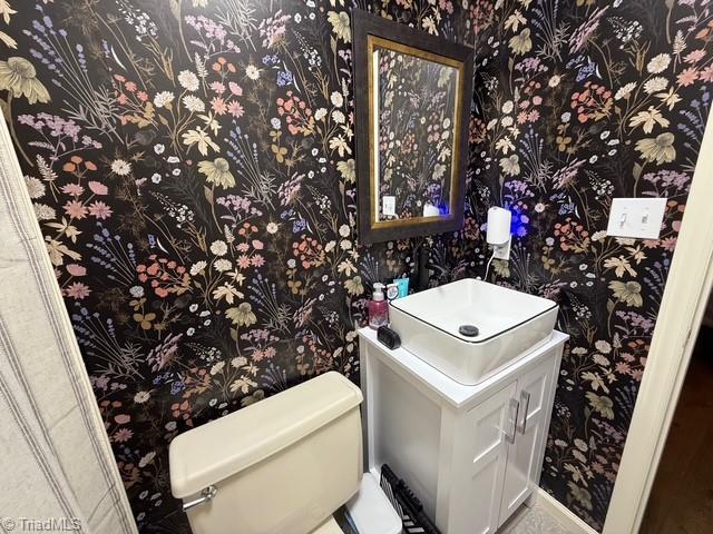 7098 E Fork Rd, High Point, NC 27265 - half bath featuring wallpapered walls, toilet, and vanity