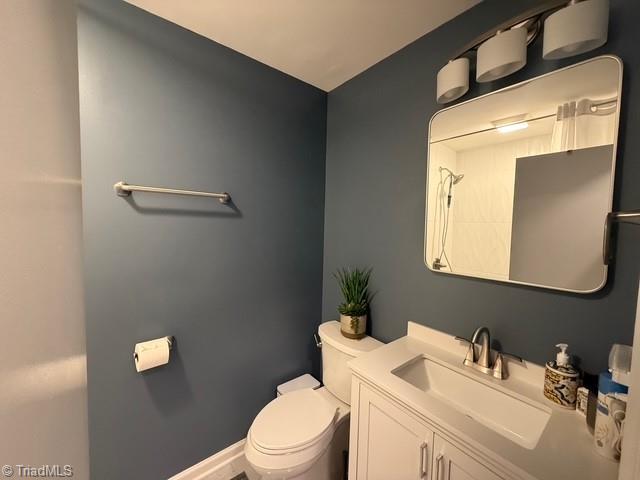 7098 E Fork Rd, High Point, NC 27265 - bathroom with toilet, vanity, and baseboards