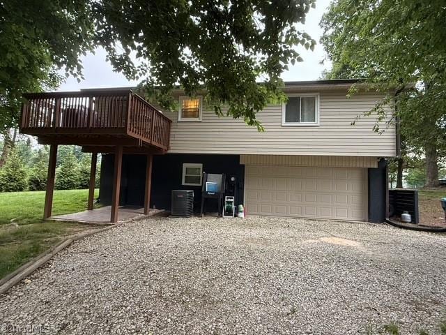 7098 E Fork Rd, High Point, NC 27265 - rear view of property featuring gravel driveway, an attached garage, central AC unit, and a deck