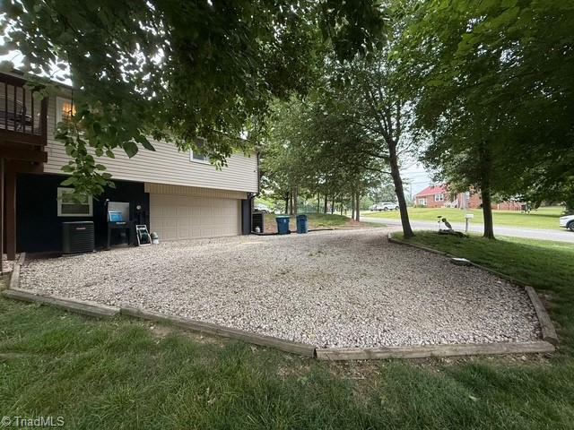7098 E Fork Rd, High Point, NC 27265 - view of side of home featuring a garage, driveway, and cooling unit
