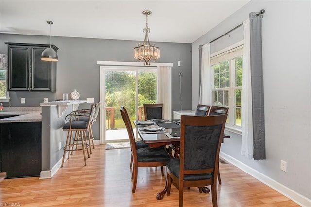 dining space with an inviting chandelier, baseboards, and light wood-style flooring