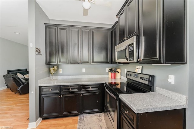 kitchen featuring appliances with stainless steel finishes, light countertops, dark cabinets, a ceiling fan, and light wood-type flooring
