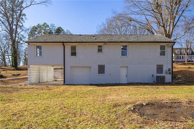 back of property featuring a garage, central air condition unit, and a yard