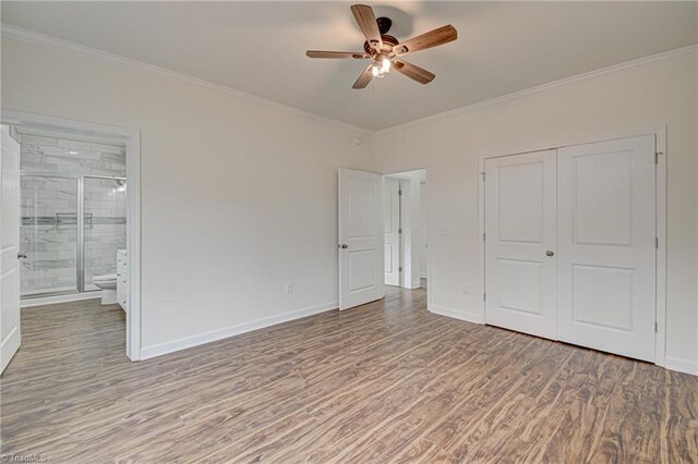 unfurnished bedroom with baseboards, a closet, crown molding, and wood finished floors