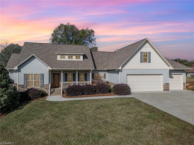 view of front of home with a garage, a yard, and a porch