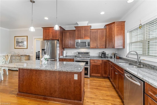 kitchen featuring stainless steel appliances, light hardwood / wood-style floors, sink, decorative light fixtures, and a kitchen island